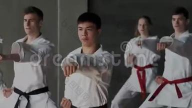 一群年轻的男女运动员在<strong>跆拳道</strong>学校练习武术。 白色和服，专注的头脑和脸